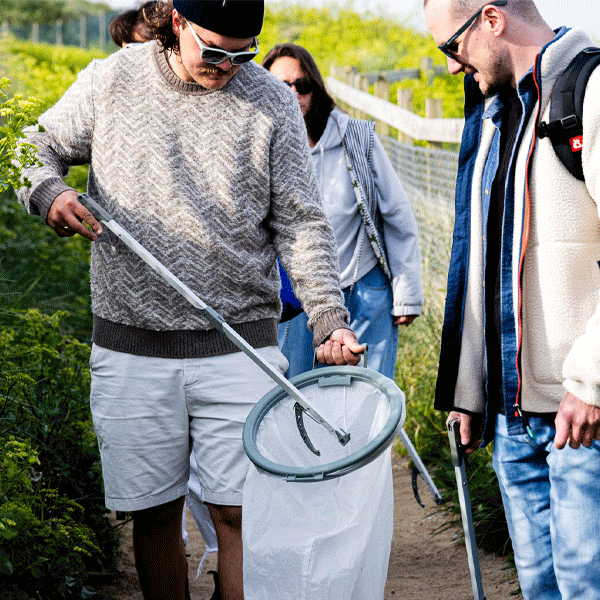 Group of people using litter pickers to clean up a path