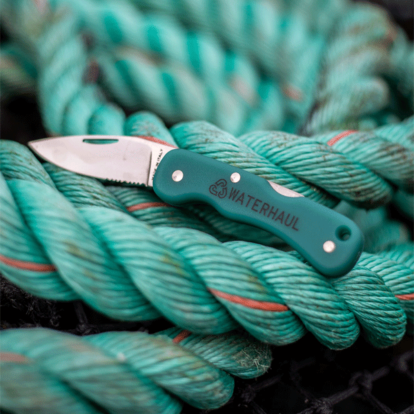 Pocket knife with green handle and silver blade on green fishing ropes