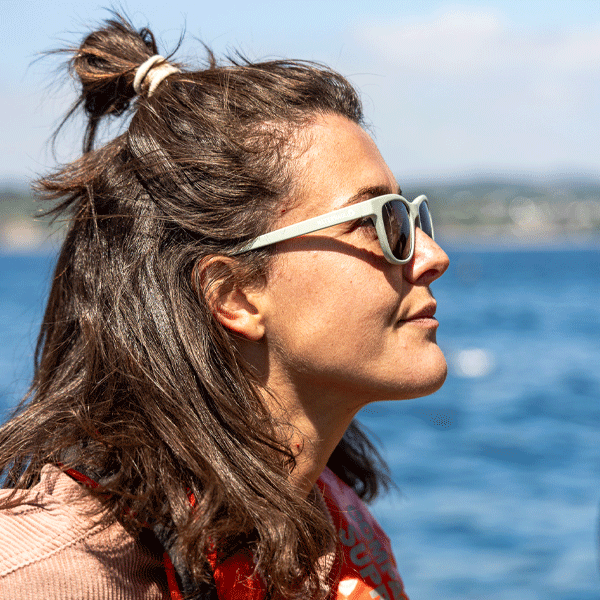 Woman wearing sunglasses with a blurred background of water and sky