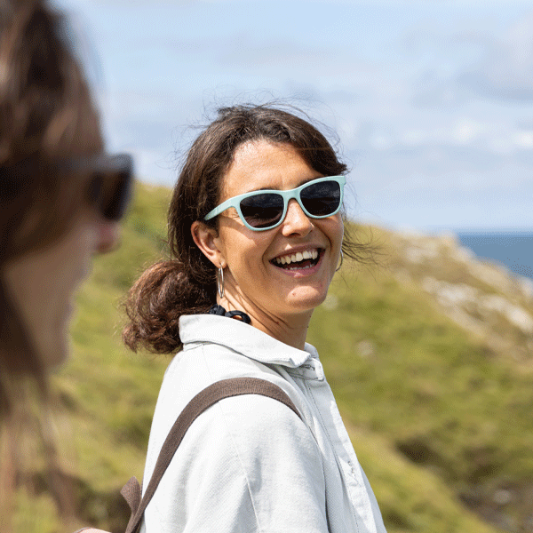 Woman wearing sunglasses and a white shirt with a scenic background