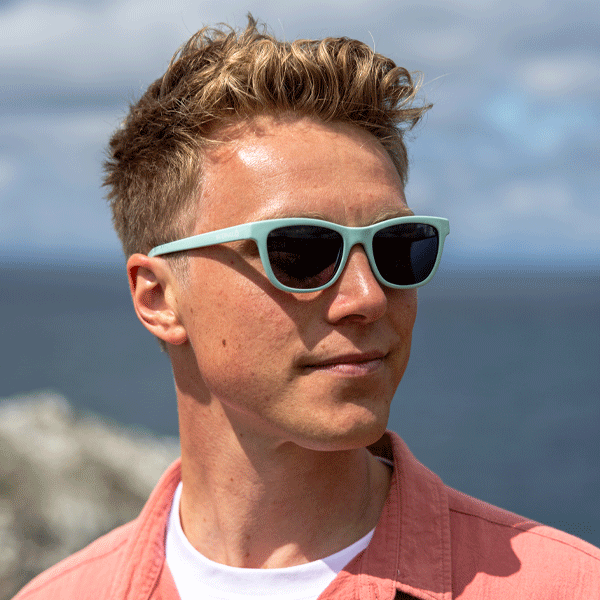 Man wearing light blue sunglasses with a blurred natural background