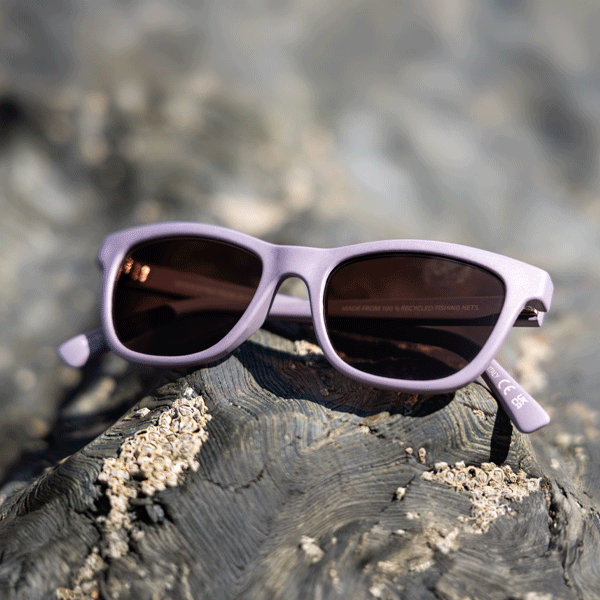 Purple sunglasses with dark lenses on a textured surface