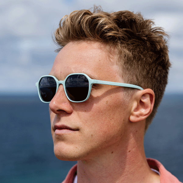 Man wearing light blue sunglasses against ocean background