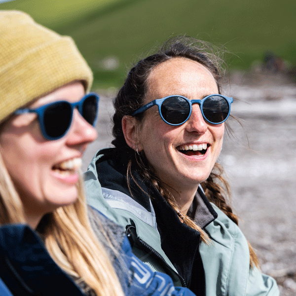Woman wearing navy blue round sunglasses in a natural setting