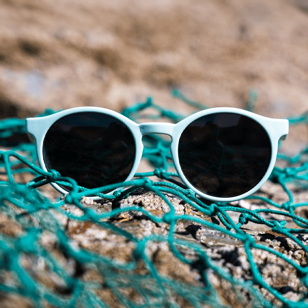 Sunglasses set against a rocky background with green fishing nets.