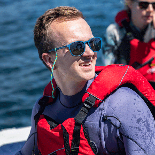 Man wearing blue sunglasses on a boat with ocean in background