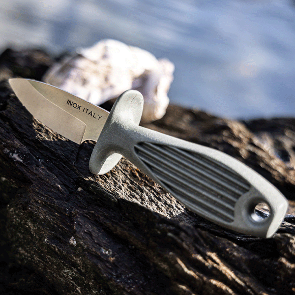 Oyster shucking knife with silver blade and green recycled handle on rocky surface