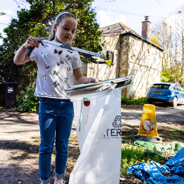 Girl using a litter picker to collect trash outdoors